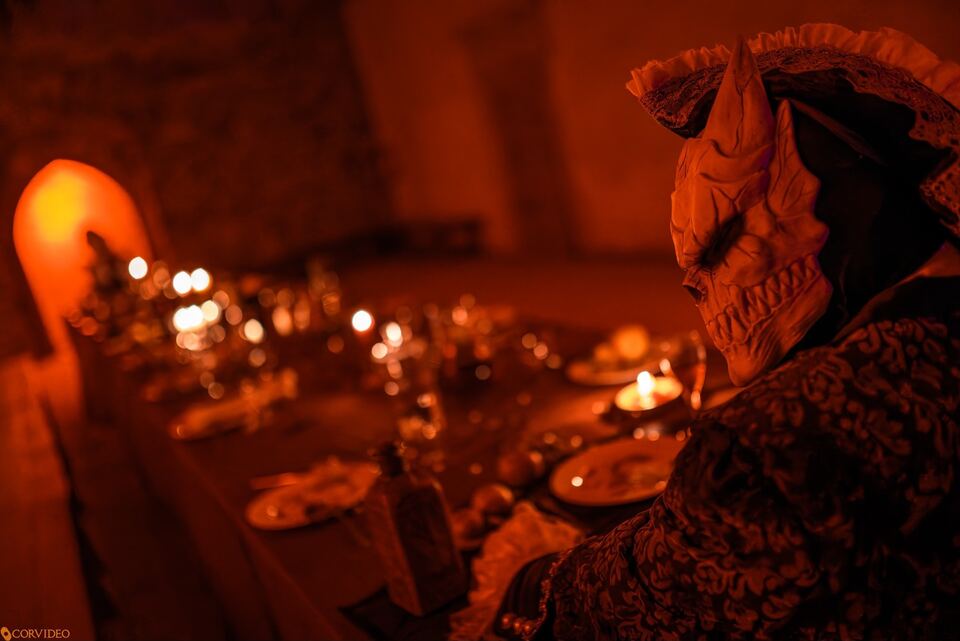 Demon przy stole ze świecami, upiorna uczta
